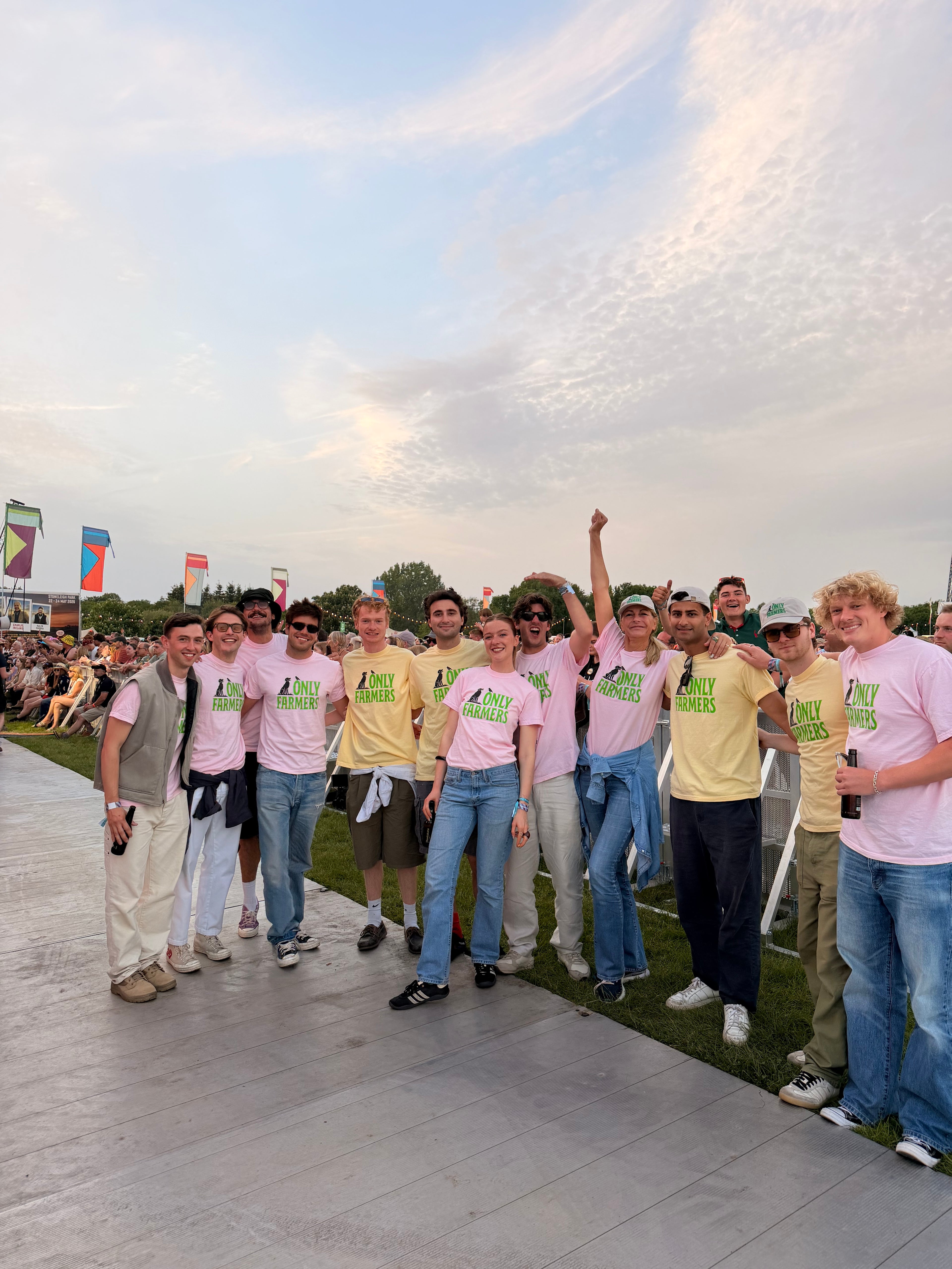 Group of people posing for a photo in a field with a crowd in the background